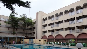 Una piscina rodeada por un edificio con varios balcones y una zona de estar cubierta.
