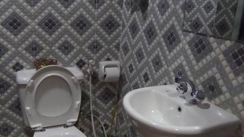 A bathroom with a toilet and a sink, tiled walls, and a hanging towel.