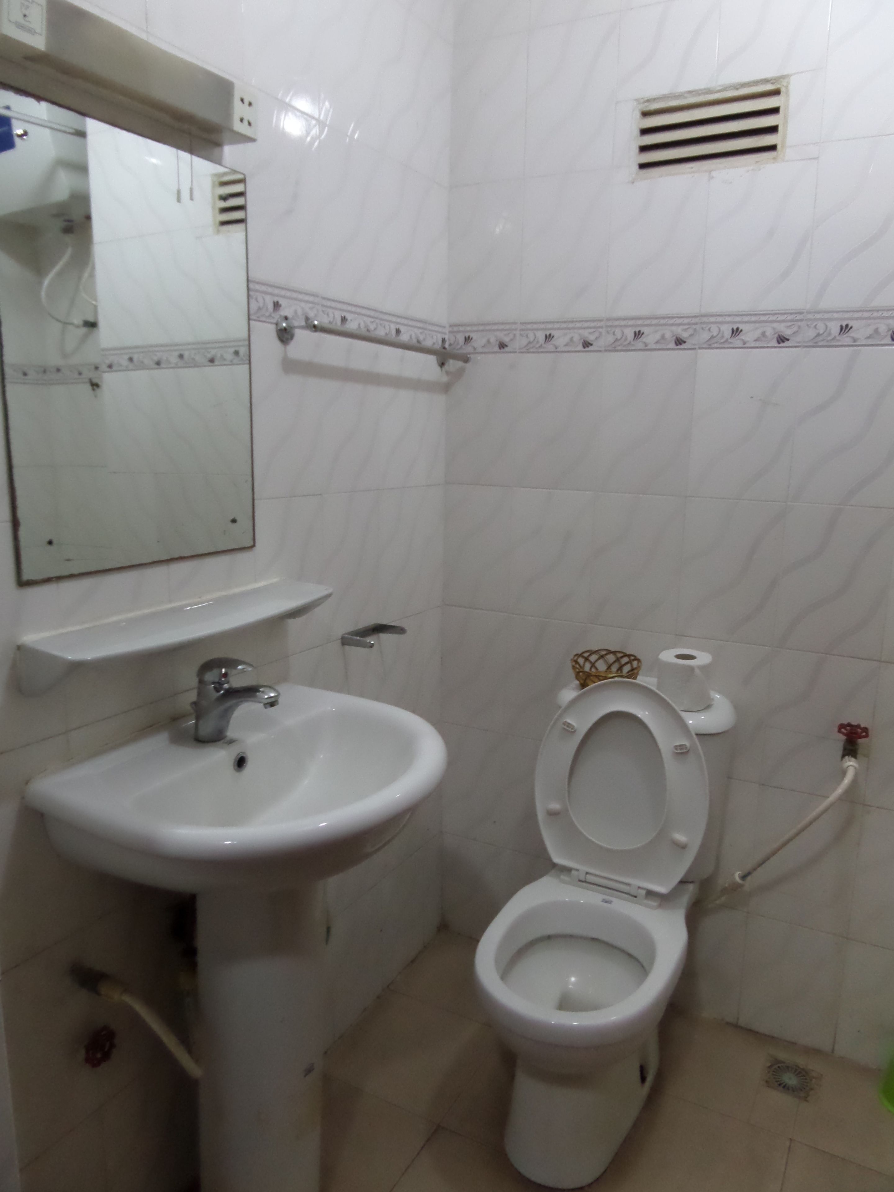 Un baño con lavamanos blanco, inodoro y espejo.