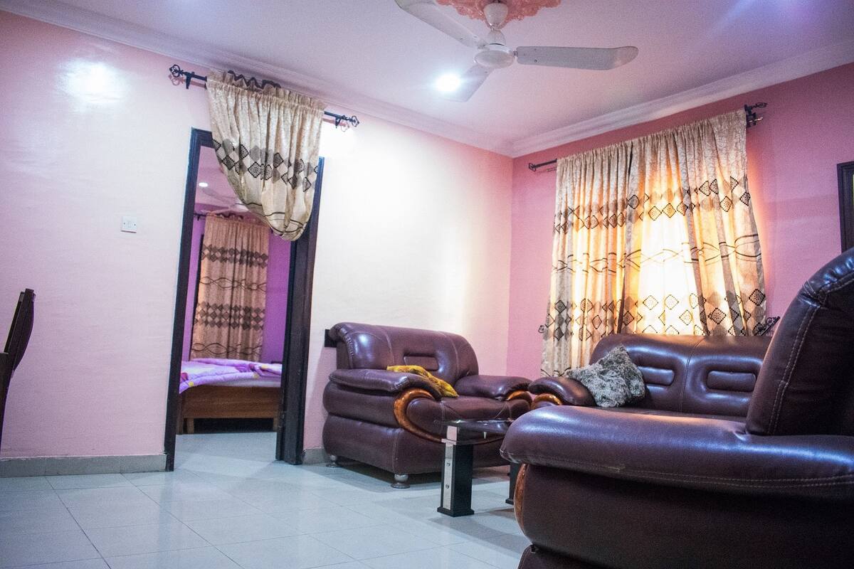 A living room with a sofa, a chair, a small table, and a ceiling fan.