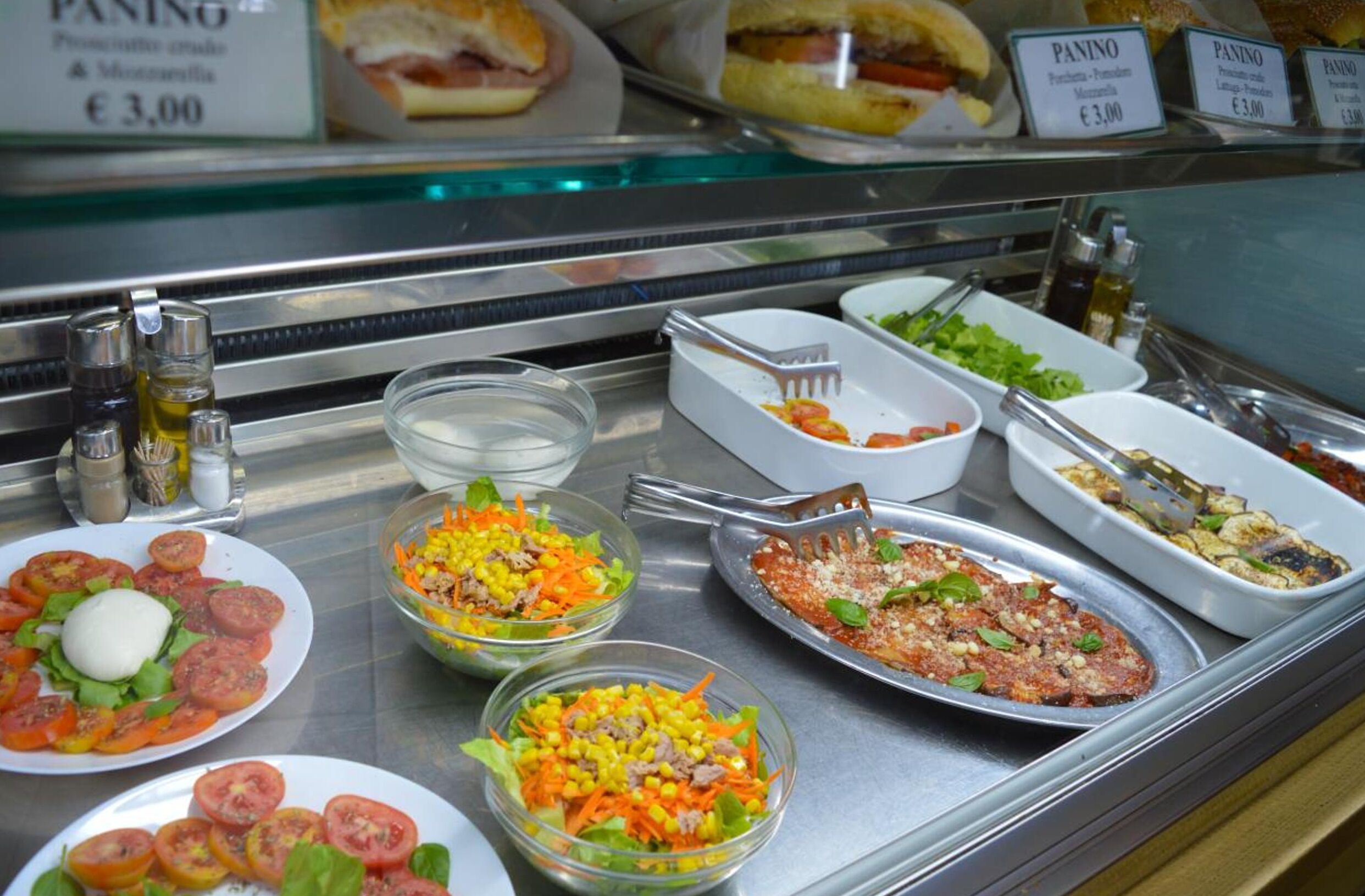 A buffet with various dishes including salads, pasta, and sandwiches.