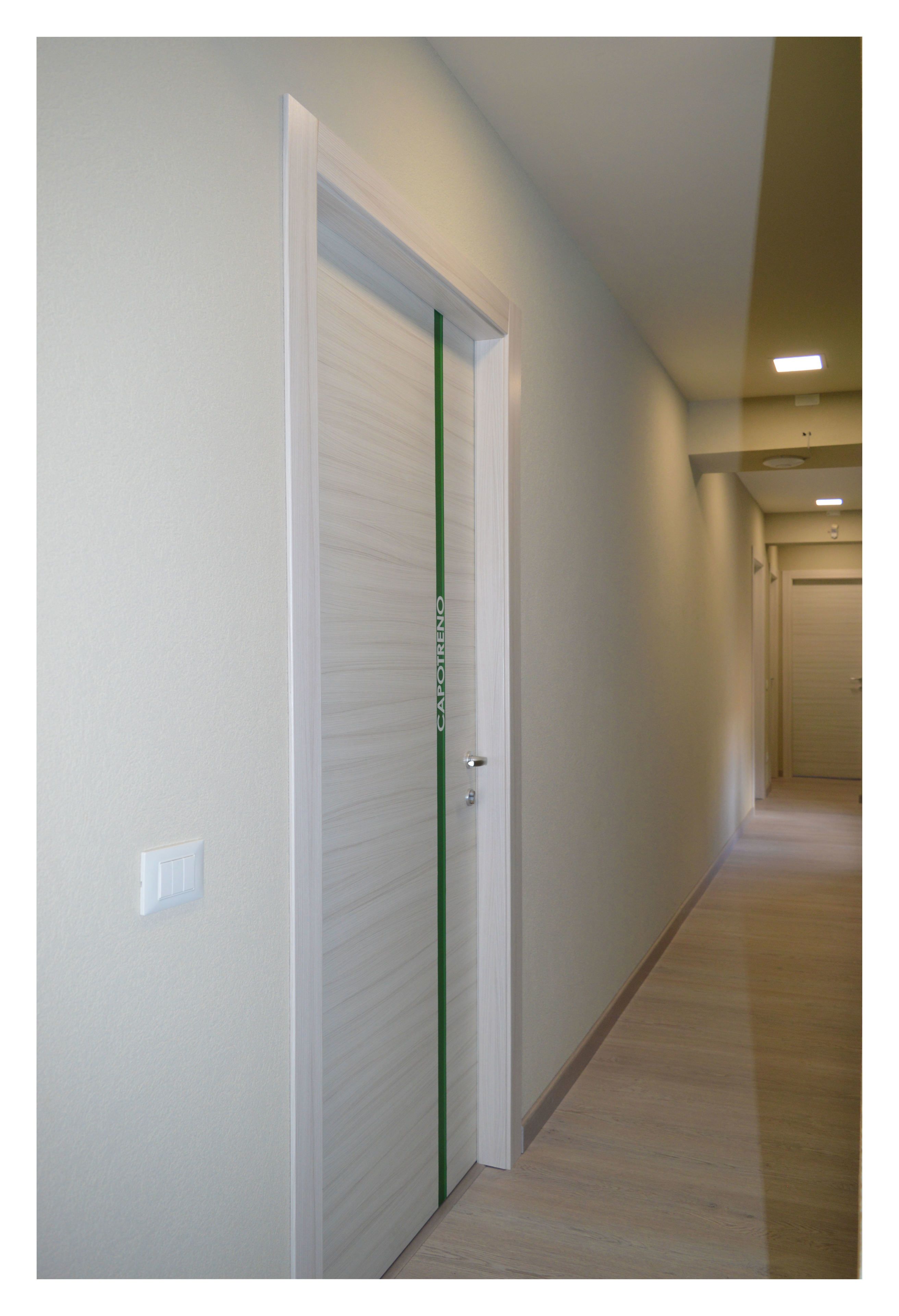 A hallway with a closed door, a light switch, and a ceiling light.