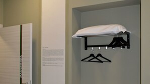 A hallway with a closed door, a wall-mounted shelf with a white pillow, and a drying rack. - B&B Stazione Dittaino (Assoro)