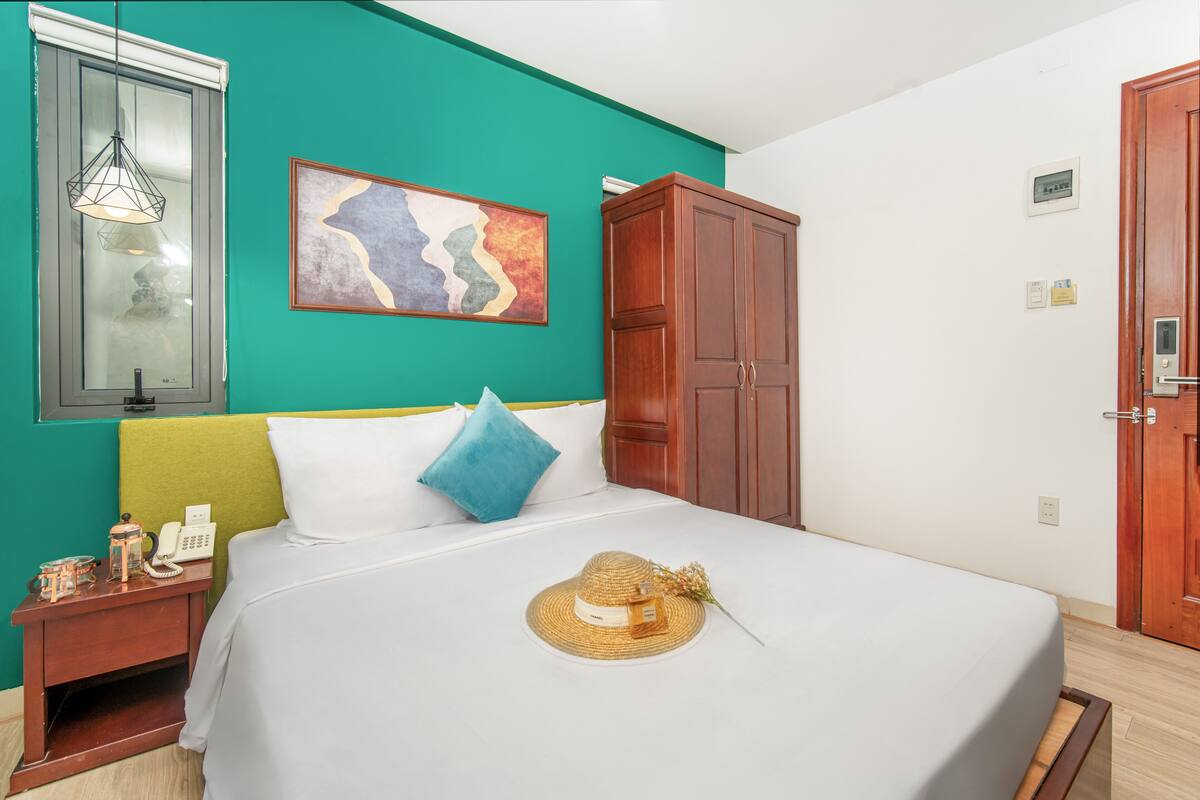 Un dormitorio ordenado con cama, mesita de noche, armario y una obra de arte colgada en la pared.