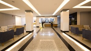 Un área de recepción de hotel moderna con mostrador de recepción, zona de estar y piso pulido.