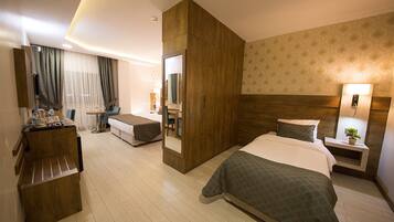 Habitación de hotel con cama, escritorio, silla, espejo y mesita de noche con lámpara.