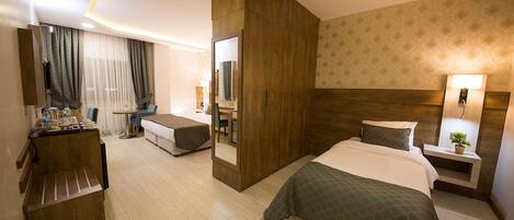 Habitación de hotel con cama, escritorio, silla, espejo y mesita de noche con lámpara.