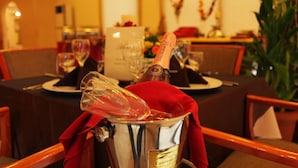 Une table à manger avec une bouteille de champagne dans un seau à glace, des verres et un menu.