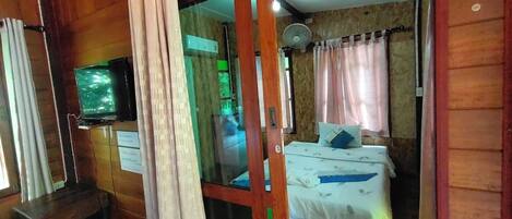 A room with a bed, a television, and a sliding door.