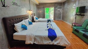 Una camera d'albergo con un letto grande, un divano verde, una televisione a schermo piatto e un murale sulla parete.
