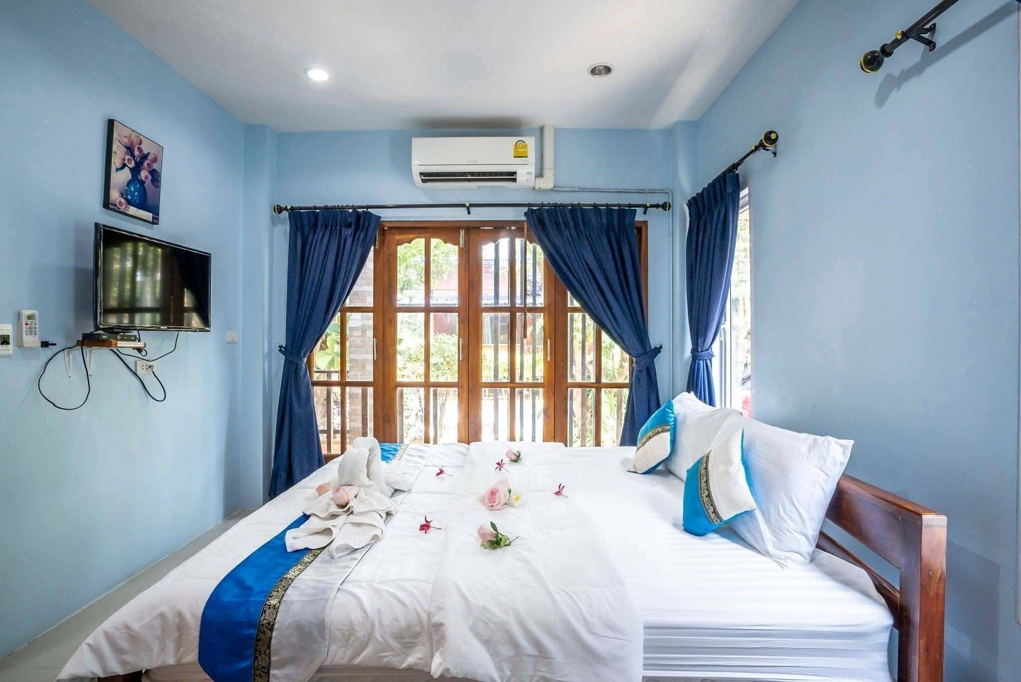 Une chambre d’hôtel avec un lit, des rideaux, un appareil de climatisation, une télévision et une fenêtre donnant sur un paysage agréable.