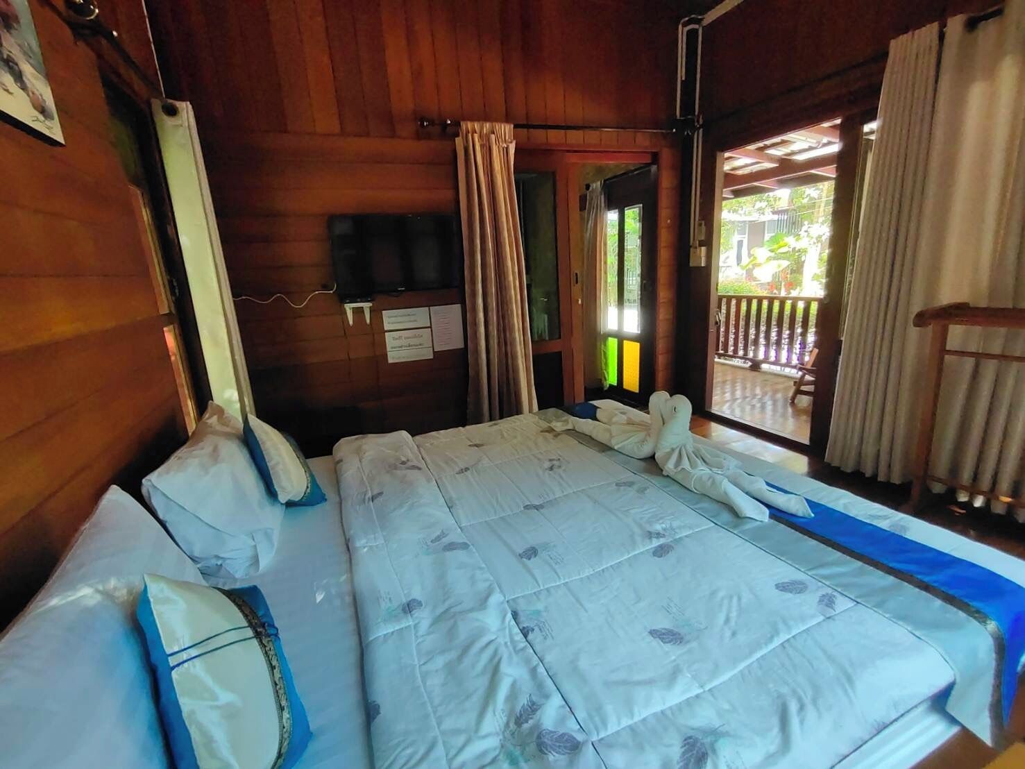 Una habitación con cama, televisión y ventana con cortinas.