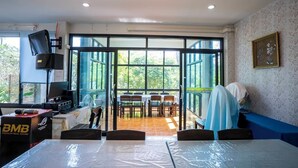A conference room with a large table, chairs, and a view through glass doors to an outdoor area.