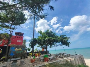 A beachside view with a red building, palm trees, and a clear sky. - Phangpring Beach Resort (Tha Sala)