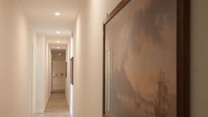 A hallway with a wooden floor, framed artwork on the walls, and recessed lighting. - Dimora Delle Arti (Naples)
