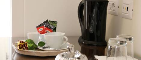 Un coin café avec une machine à café, des tasses et une théière, le tout posé sur une table.