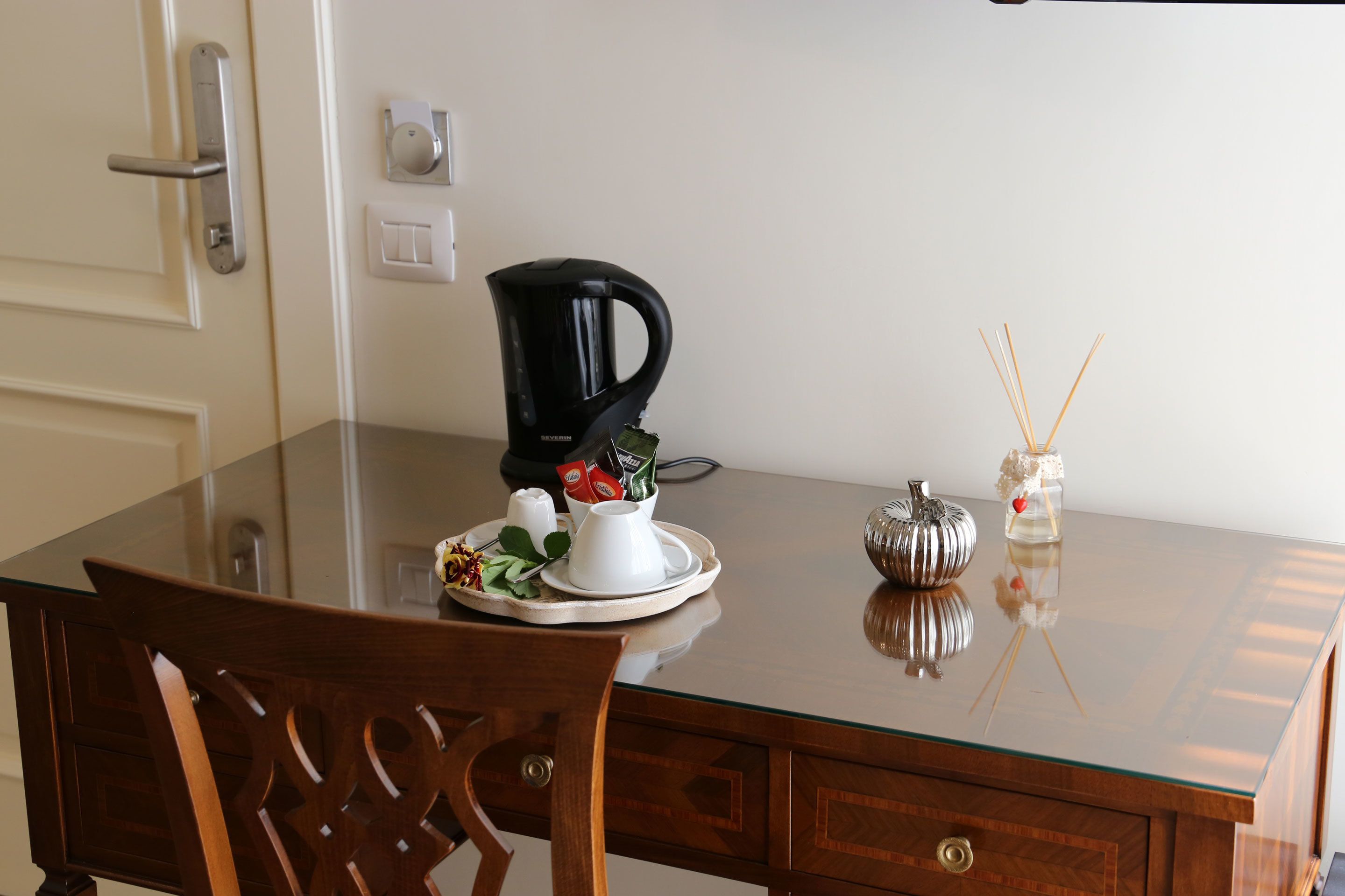 Uma mesa de jantar com uma cafeteira, um bule branco e uma abóbora decorativa.