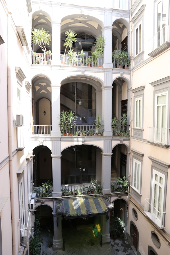 A multi-story building with balconies, arched doorways, and potted plants.