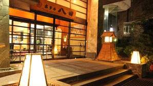 A traditional Japanese building with a wooden entrance, a stone pathway, and a lantern. - Hotel Hatta (Fuefuki)