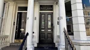 A building with a black door labeled "Saint James" and the numbers "19" and "21" on the columns. - Saint James Backpackers (London)
