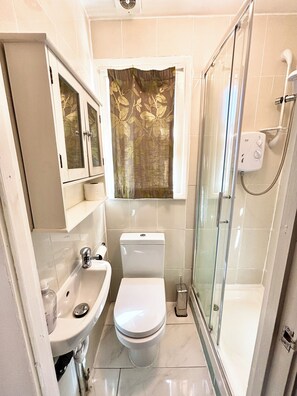 Un baño pequeño con inodoro, lavamanos y cabina de ducha de vidrio.