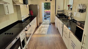 A modern kitchen with a central island, black countertops, and wooden flooring. - Saint James Backpackers (London)