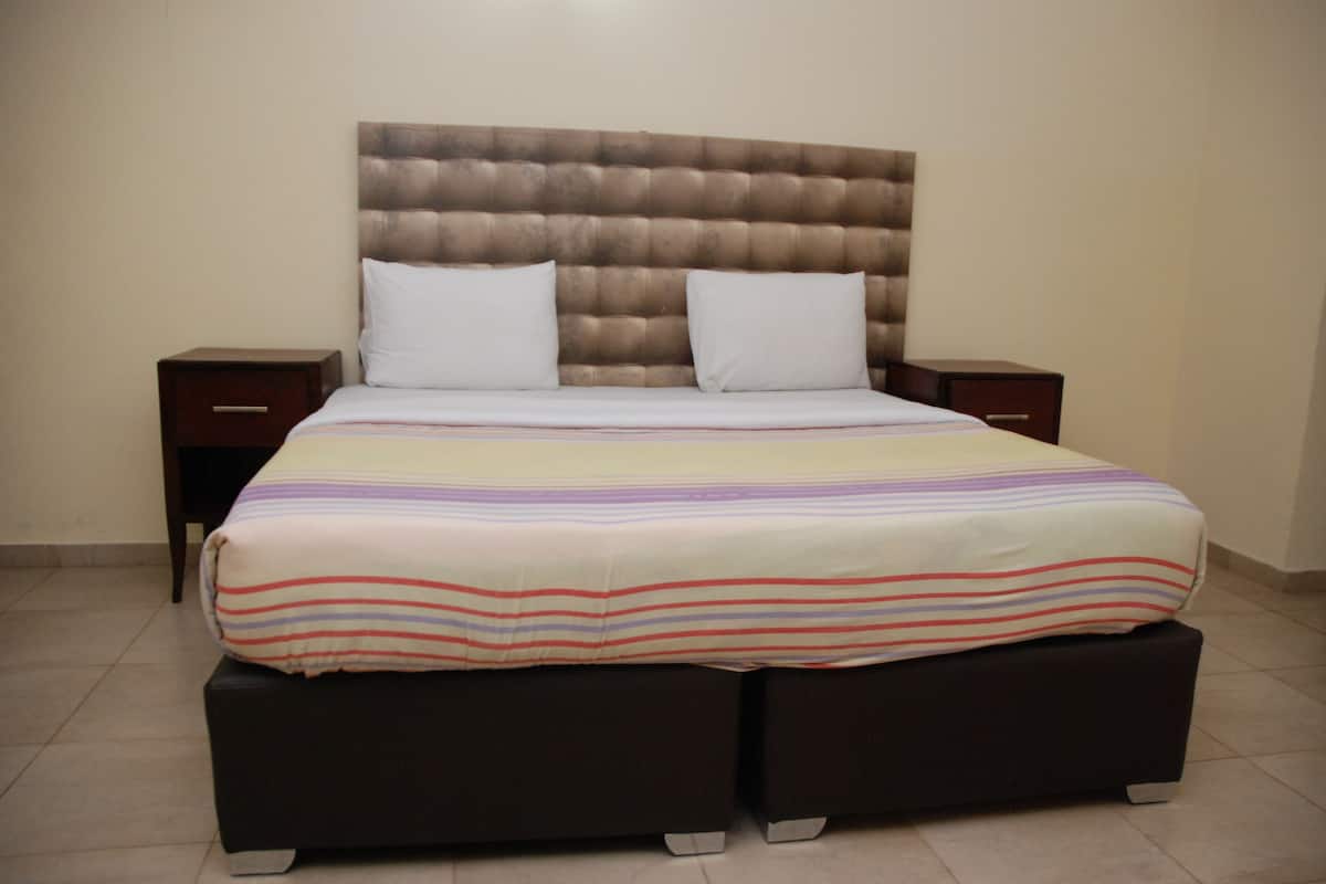 A bed with a tufted headboard, two white pillows, and a striped bedspread.