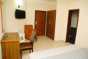 A hotel room with a bed, a desk, a chair, a television, and a wardrobe. - Lucky Sunshine Hotel (Lagos)