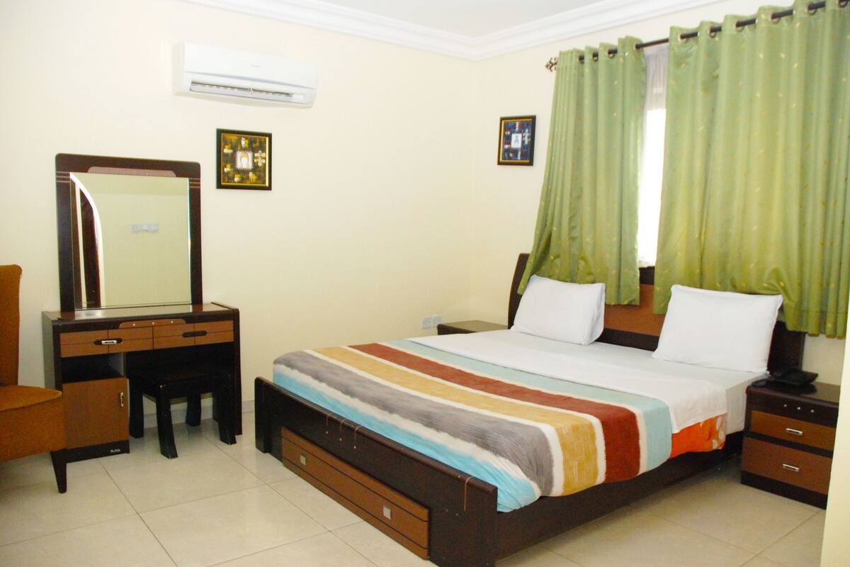 A bedroom with a bed, a dresser, a mirror, and a nightstand.