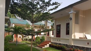 Un patio con un árbol, un sendero y un edificio con puerta roja y ventanas.