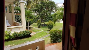 Vista desde un balcón sobre un jardín cuidado con palmeras y un camino de piedra.