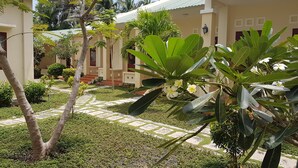 Un patio con un sendero, palmeras y un edificio con techo de tejas.