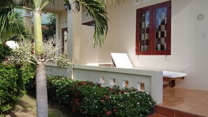 Una habitación con cama, ventana con cortinas, una mesita y una silla.