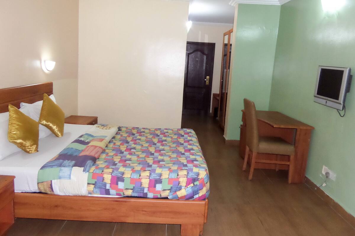 A hotel room with a wooden bed, a desk, and a chair.
