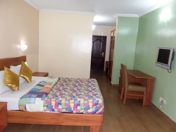 Habitación de hotel con una cama de madera, un escritorio y una silla.