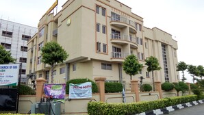A multi-story building with balconies, a sign for the Church of God, and a banner for the Praise Arena. - Le Real Hotel (Lekki)