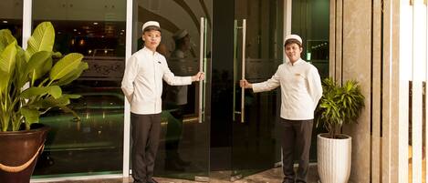 Two individuals in white uniforms opening a glass door.