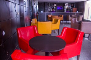 Un espace bar comprenant un comptoir, des tabourets de bar et un écran de télévision.