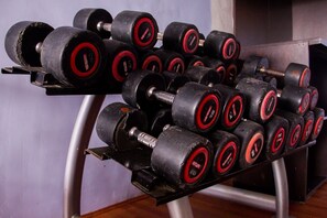 A rack of black dumbbells with red accents, arranged on a metal stand. - Paris Suites (Lagos)