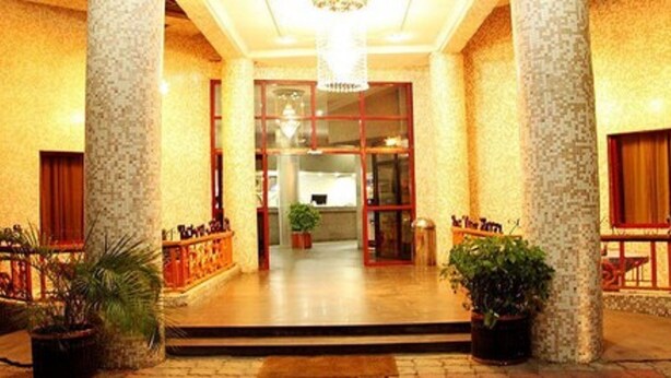 A hotel entrance with a tiled facade, a central doorway, and potted plants. - Rockview Hotel Festac (Lagos)