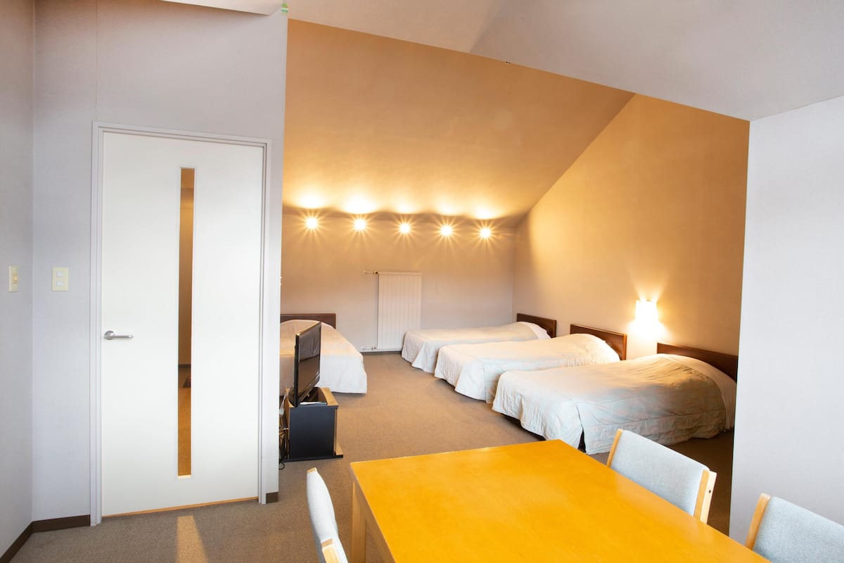 A hotel room with a single bed, a desk, a chair, and a table.