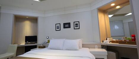 A modern hotel room with a bed, desk, and a large mirror.