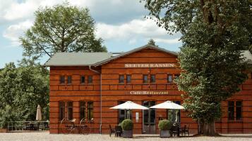 Een gebouw van baksteen met het bord 'SEETERRASSEN Café-Restaurant' en terras met parasols.