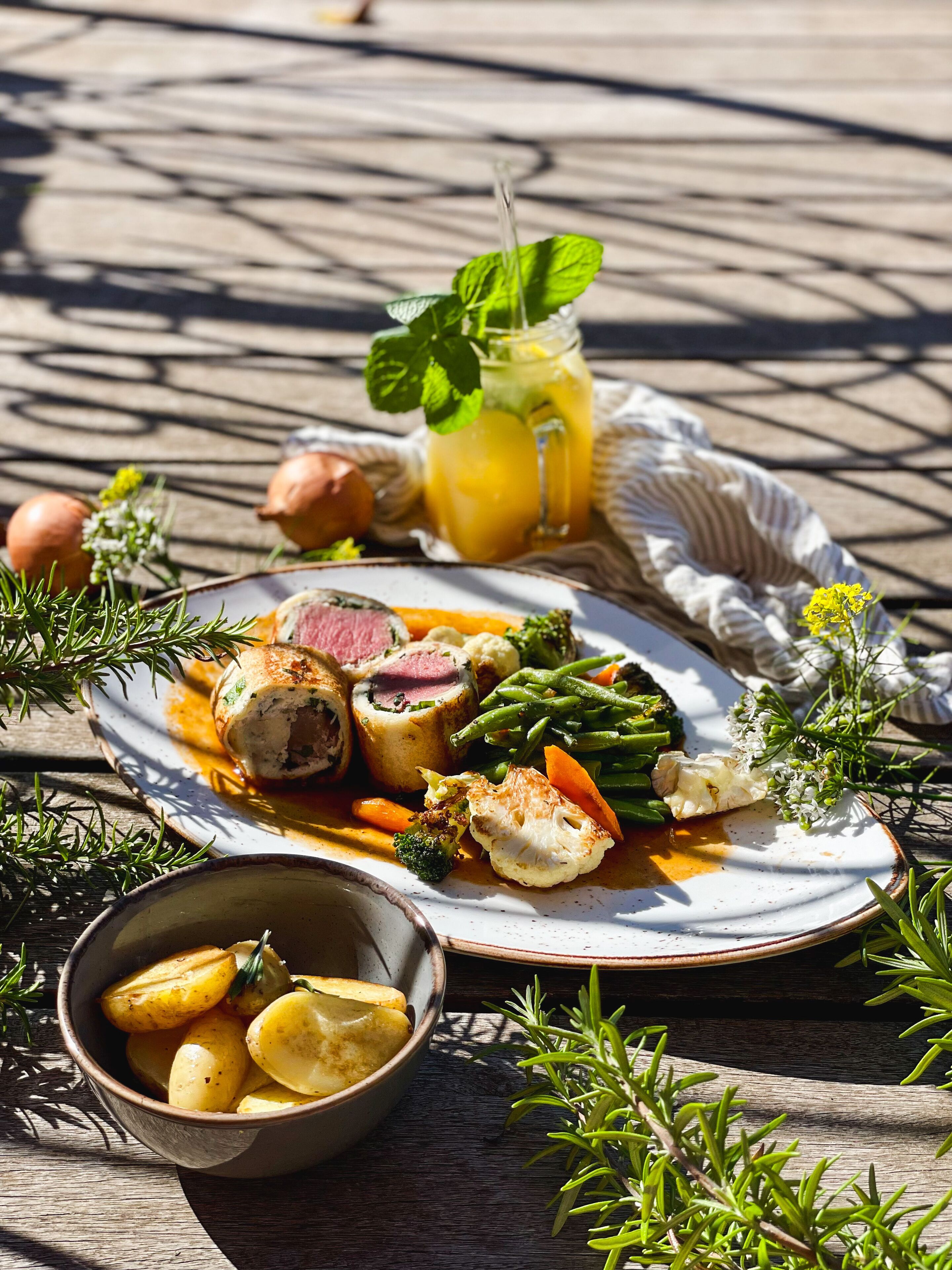 A meal with meat, vegetables, and potatoes on a wooden table.