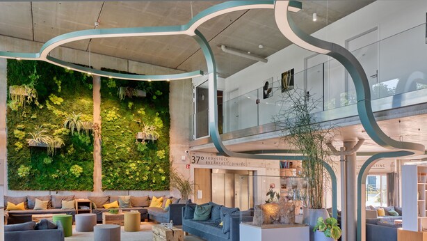 A spacious lobby with a green wall, seating area, and a staircase leading to an upper level.