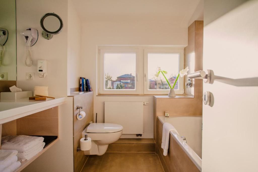 A compact bathroom with a toilet, a sink, a mirror, and a window.