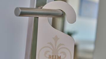 A door handle with a metallic finish and a keyhole, accompanied by a card with the text "BEIM TRÄUMEN" engraved on it.