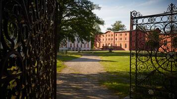 A pathway leading to a building with a red facade and arched windows.