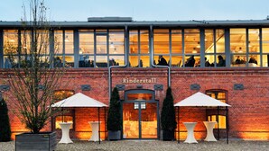 A brick building with large windows and a sign reading "Rinderstall".