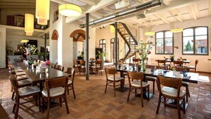 A spacious dining area with high ceilings, exposed beams, and a long communal table surrounded by chairs.